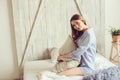 Young woman in pajama wake up in the morning in cozy scandinavian bedroom and lying on bed with oversize knitted blanket Royalty Free Stock Photo