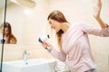 Young woman pampering with hairdryer at the mirror