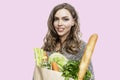 Young woman with a paper bag with groceries. Beautiful smiling blonde. Healthy food, vitamins and veganism. Isolated on a pink