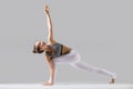 Young woman in Parivrtta Parsvakonasana pose, grey studio backgr Royalty Free Stock Photo