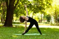 Young woman in park practicing yoga. Trikonasana Triangle Pose Royalty Free Stock Photo