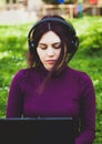 Young woman in park using laptop computer listening music Royalty Free Stock Photo