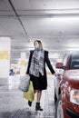 Young woman in a parking lot near a car. Girl after shopping.