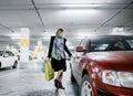 Young woman in a parking lot near a car. Girl after shopping.