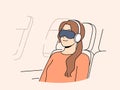 Young woman passenger flight with blindfold and earphones sleeps in airplane chair