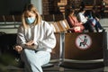 Young woman passenger in medical mask opens a laptop while sitting in the airport waiting room. Traveler sits in the airport Royalty Free Stock Photo