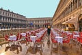 Young woman passes through the red chairs of a historic cafÃÂ© in the middle of the San Mark`s square flooded