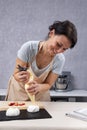 Young woman pastry chef fills cream brownies with pastry bag. Process of making Cake Anna Pavlova