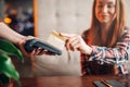 Young woman pay by mobile phone in cafe