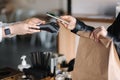 Young woman paying bill through smartphone using NFC technology in a cafe. Female customer paying using contactless Royalty Free Stock Photo