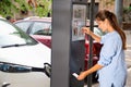 Young woman paying for parking in modern parking meter on city street Royalty Free Stock Photo