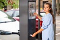 Young woman paying for parking in modern parking meter on city street Royalty Free Stock Photo