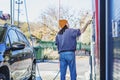 A young woman pays for a self-service car wash in the countryside