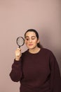 Young woman peering through a magnifying glass