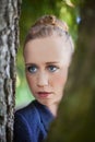 Young Woman Peering Through Tree Trunks