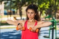 Young woman performs exercises with dumbbells on the playground on a warm sunny morning. Healthy lifestyle concept