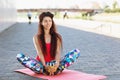 Young woman performs morning exercises while sitting on a gymnastic mat outdoors