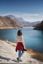 A young woman photographer with a photo camera in her hand stands on the shore of a high mountain lake on a sunny day Royalty Free Stock Photo