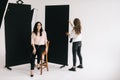 Young woman photographer is preparing backdrop in studio for photo shoot.