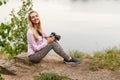 Young woman photographer sitting on the lake in summer