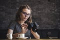 Young woman photographing chimping her photos as she sits relaxing having coffee