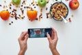 Young woman photographing muesli bowl with fruits. Healthy snack or breakfast in the morning. Royalty Free Stock Photo