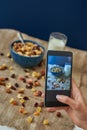 Young woman photographing muesli bowl with milk. Healthy snack or breakfast in the morning. Royalty Free Stock Photo