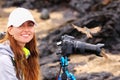 Young woman photographing on Santiago Island with Galapagos flycatcher on her lens hood, Galapagos National Park