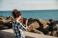 Young woman photographs the sea and rocks on her mobile phone Royalty Free Stock Photo