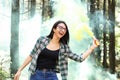 Young woman in a photoshoot raising her hand holding a smoke bomb yellow in the forest smiling at Costa Rica Royalty Free Stock Photo