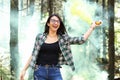 Young woman in a photoshoot raising her hand holding a smoke bomb yellow in the forest smiling at Costa Rica Royalty Free Stock Photo