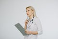 Woman physician with stethoscope prescribing treatment to patient. Female doctor with pen writing recipe on clipboard Royalty Free Stock Photo