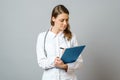 Young woman physician with stethoscope prescribing treatment to patient