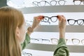 Woman pick a eyeglasses from shelf in optics store