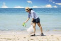 Young woman picking plastic waste on beach