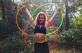 a beautiful woman standing next to some colorful hoops in the woods