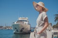 Young woman at the pier with sailing yachts. A beautiful girl enjoing vacation in front of moored sport yachts on a hot Royalty Free Stock Photo