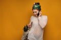 Young woman with a pineapple in her shopping bag talks on phone over yellow background Royalty Free Stock Photo