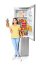 Young woman with pineapple near open refrigerator
