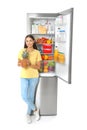 Young woman with pineapple near open refrigerator