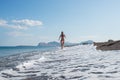 Young woman in pink bikini running alongside beautiful pebble beach Royalty Free Stock Photo