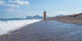 Young woman in pink bikini running on a beautiful pebble beach Royalty Free Stock Photo