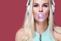 Beautiful blonde woman blowing pink bubble gum. Girl listen music in headphones. Fashion and lifestyle portrait. Royalty Free Stock Photo