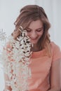 A young woman in a pink dress sitting in a chair with white dried sprig and smiling