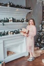 A young woman in a pink dress standing by the fireplace on the background of a Christmas tree Royalty Free Stock Photo