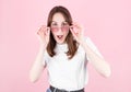 Young woman in pink glasses is very surprised looking at the camera and lowering her glasses. Surprise and shopping concept on Royalty Free Stock Photo