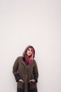 young woman with pink hair piercings and tattoos against wall with copy space