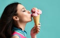 Young woman in pink hat eat strawberry ice-cream dessert in waffle cone on modern light blue