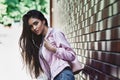 Young woman in pink jacket carrying backpack standing near wall Royalty Free Stock Photo