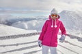 Young woman in pink jacket, wearing ski goggles, leaning on snow Royalty Free Stock Photo